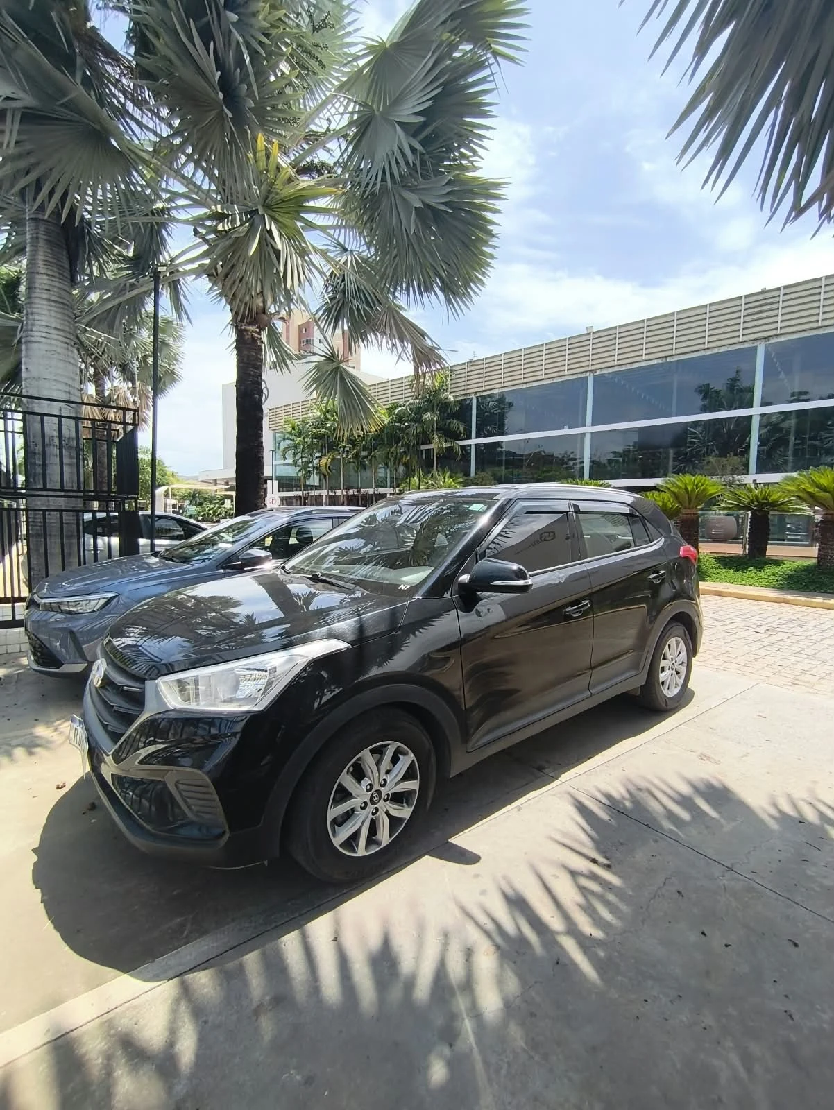SUV preto da Transfer YS em frente a um hotel entre palmeiras